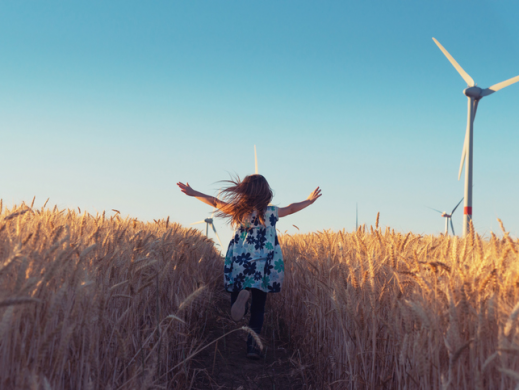 Girl in field with wind turbine