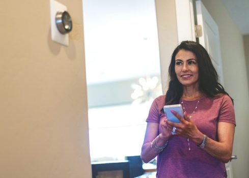 Woman Using Phone to Set Thermostat