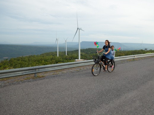 Mom and child riding a bike by windmills