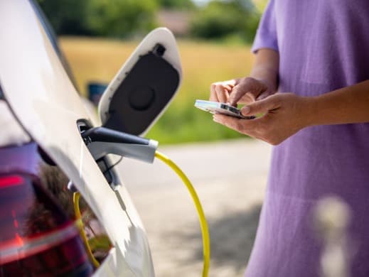 Women charging EV while looking at her phone